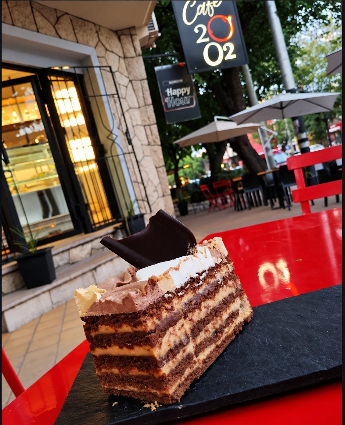 Una porción de torta en una mesa de la vereda, frente al cartel del café